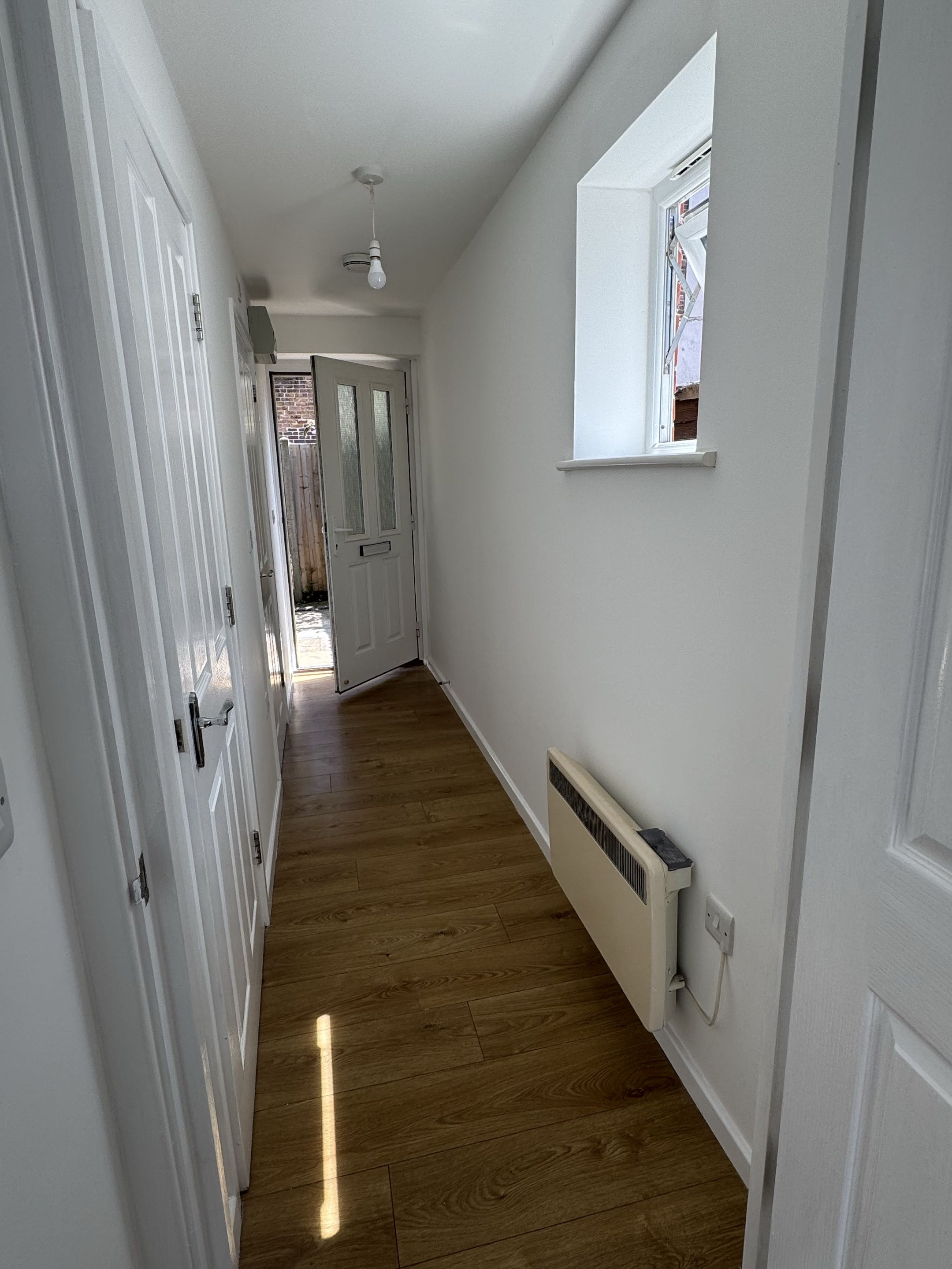 Finished apartment hallway with bright white walls and wood-effect flooring