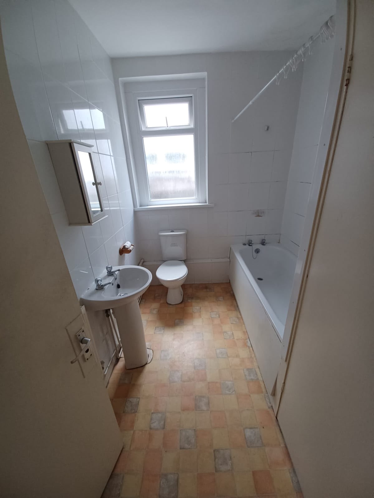Bathroom with old tiled vinyl floor and dated fittings before renovation