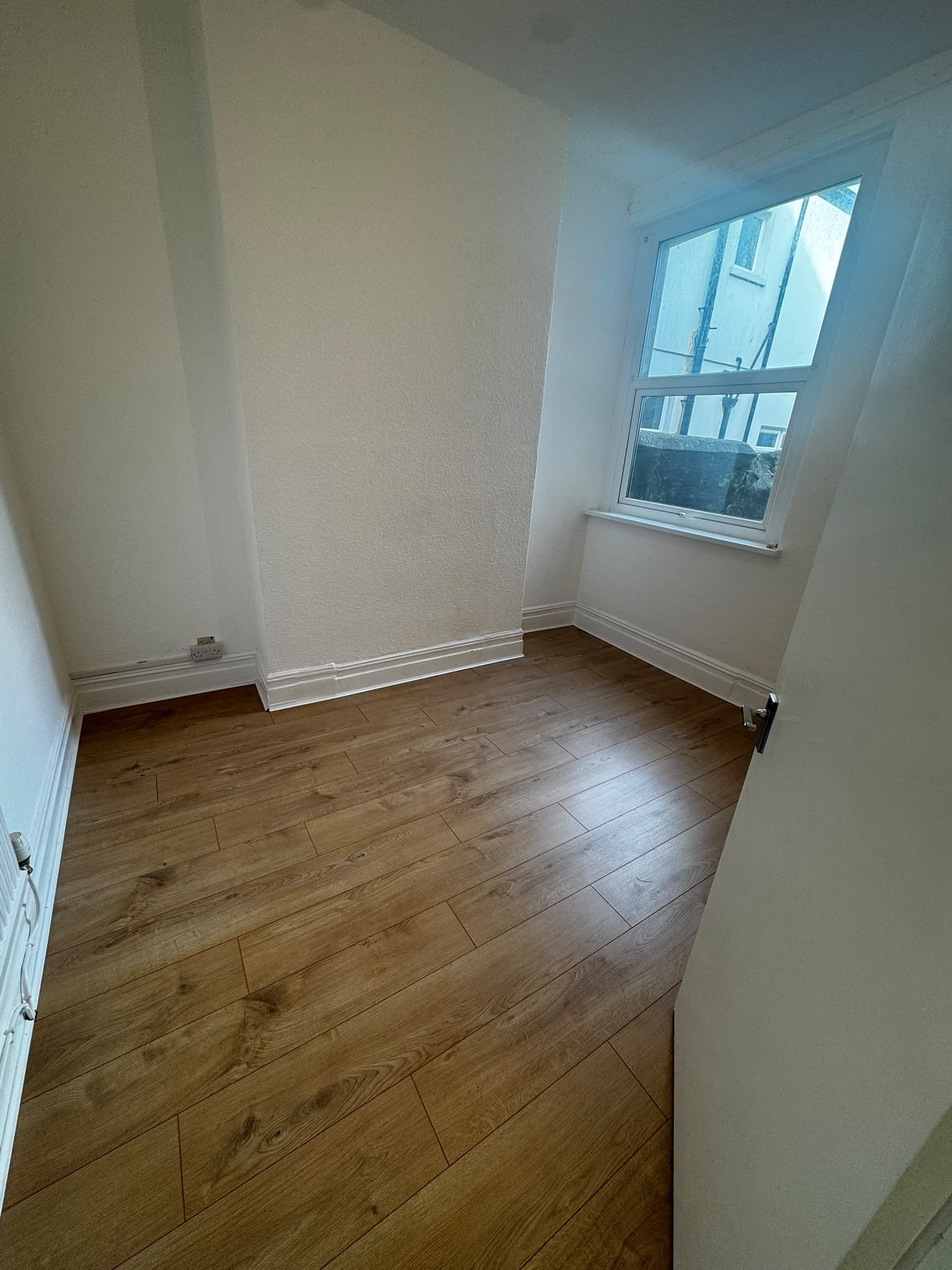 Bedroom after renovation with fresh white walls and new oak-effect flooring