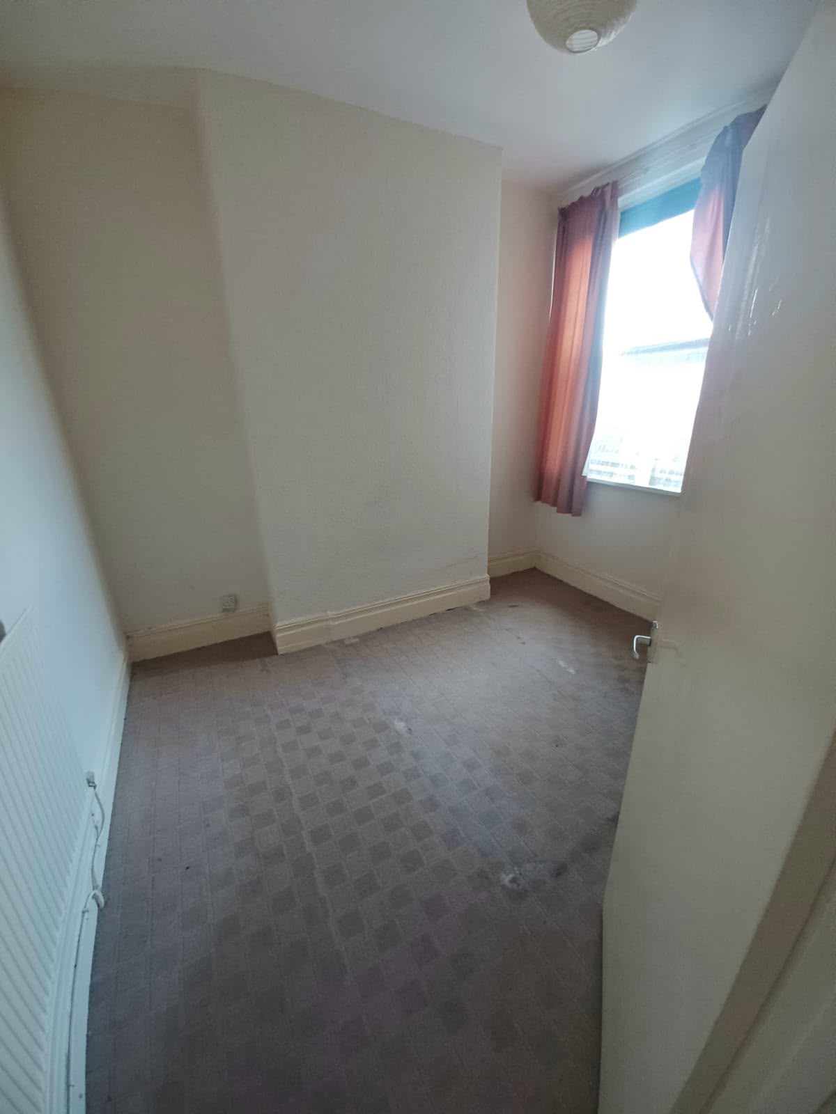 Bedroom with worn carpet and dated curtains before renovation