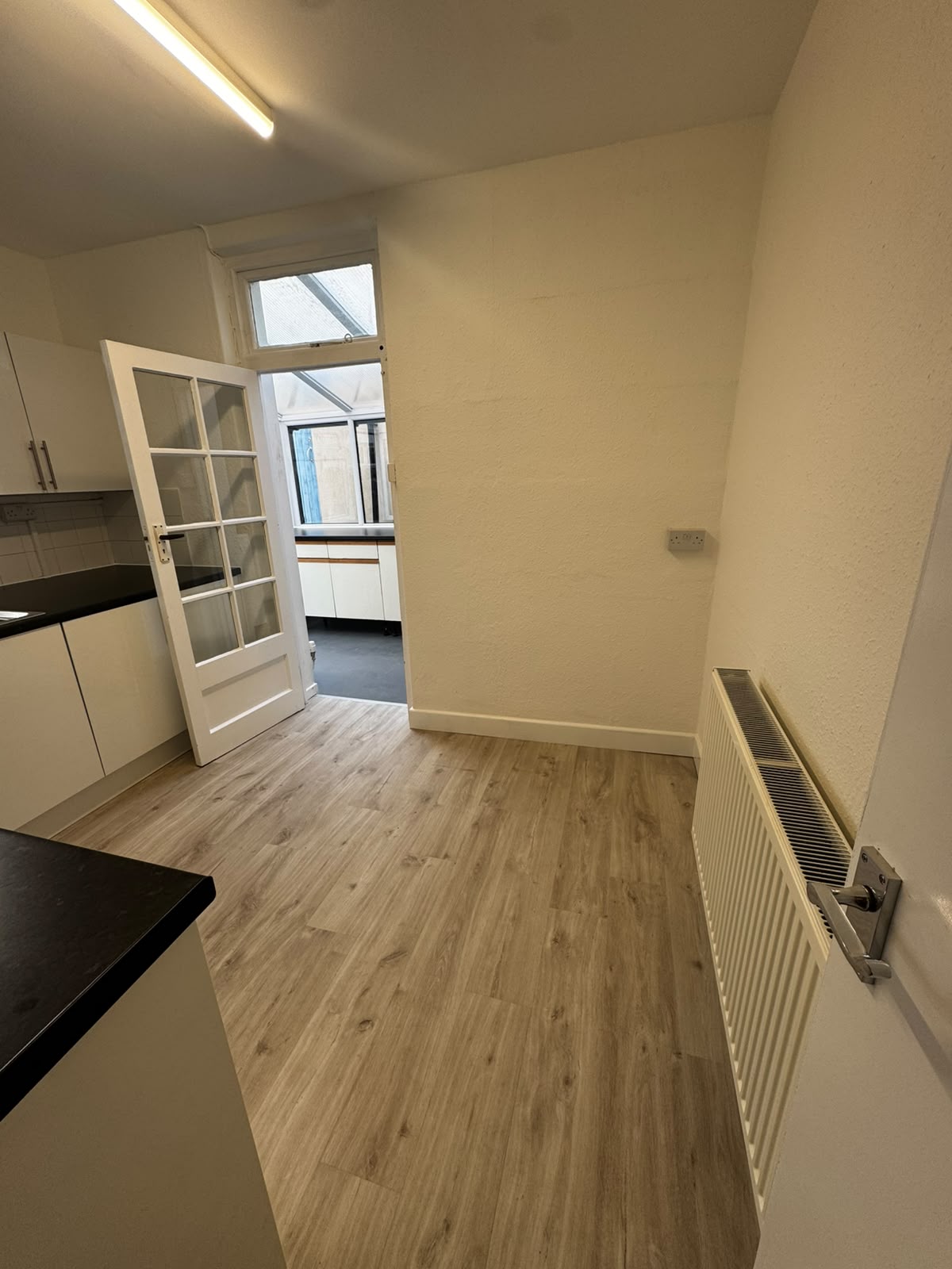 Kitchen dining area after renovation with fresh paintwork and new wood-effect flooring