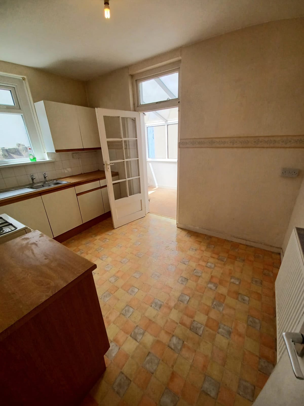 Kitchen dining area with old patterned vinyl flooring and dated wallpaper border
