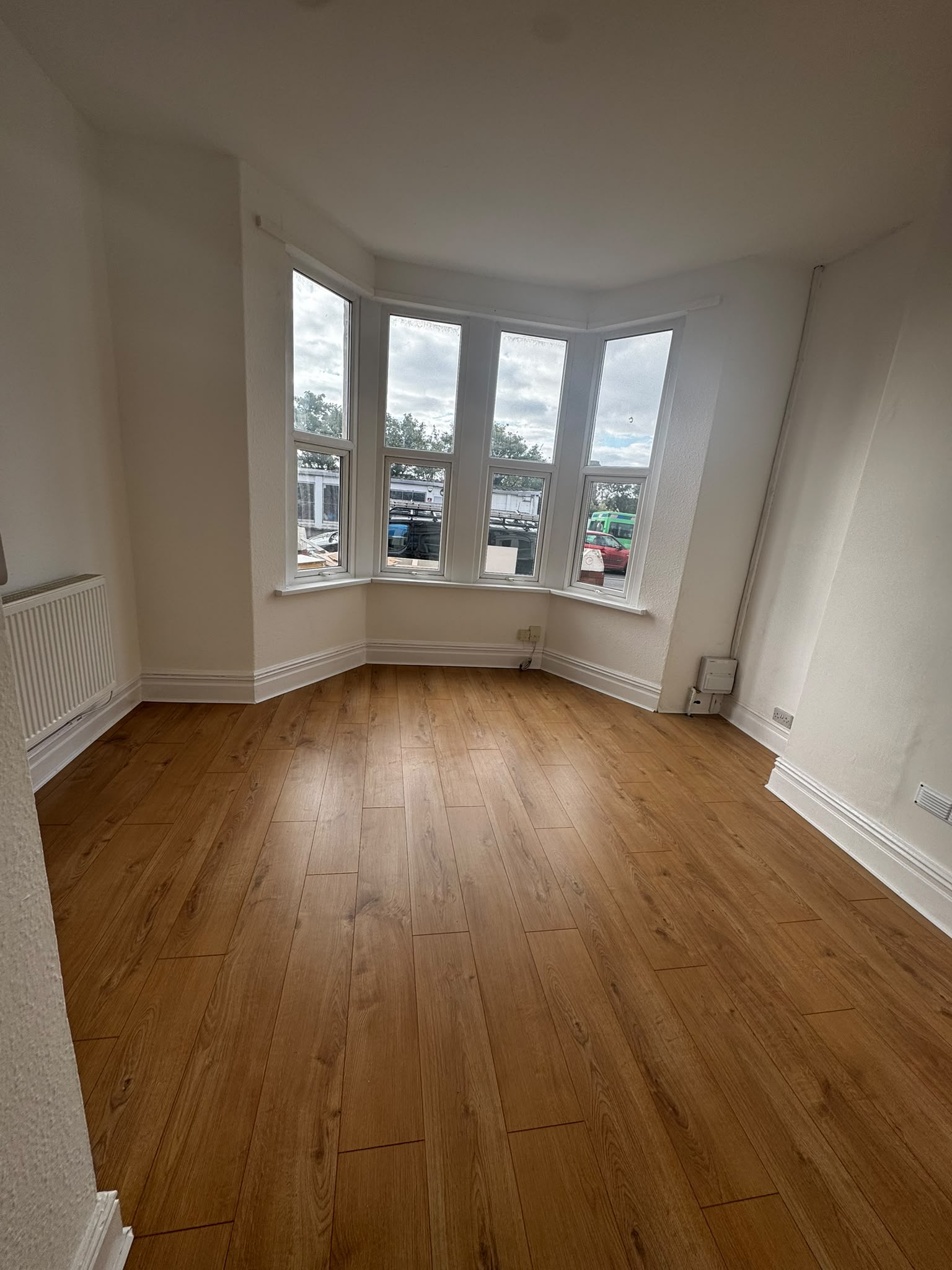 Bright living room with bay window, freshly painted walls and new oak-effect laminate flooring