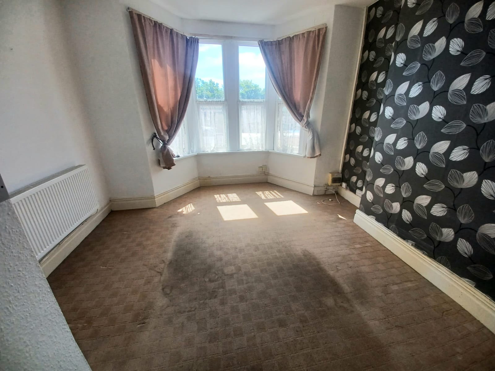 Living room with stained carpet and dark patterned feature wallpaper before renovation