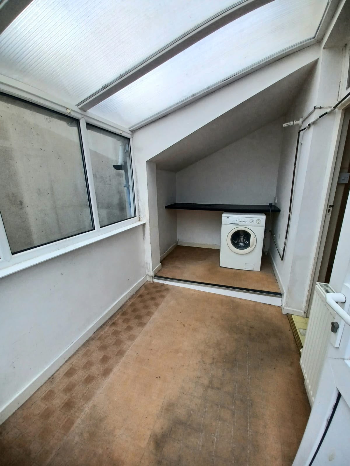 Utility room with stained flooring and grubby walls before renovation